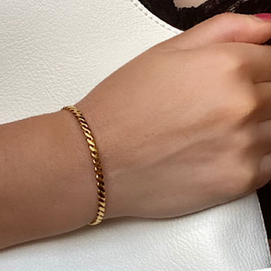 A Gold Plated Weave Cuff Bracelet on a women's wrist clutching a white bag