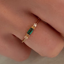 Cargar imagen en el visor de la galería, thin emerald green emerald and diamond stacking ring on 18ct yellow gold. this is worn by the hand of a white skin model
