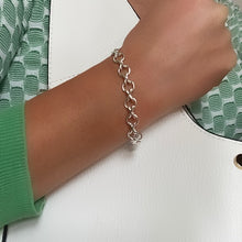 Load image into Gallery viewer, chunky sterling silver hugs and kisses handmade bracelet worn by white model wearing green and white top holding white handbag
