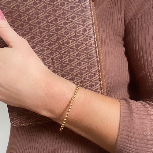 Lady wearing a brown top, holding a brown bag with a Gold Beaded Cuff Bracelet on her wrist